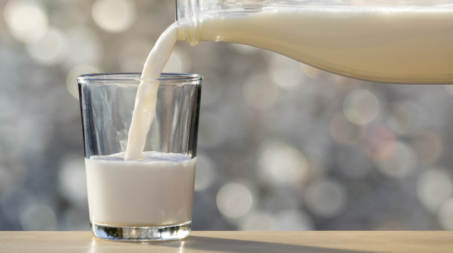 Jemand gießt Milch in ein Glas.